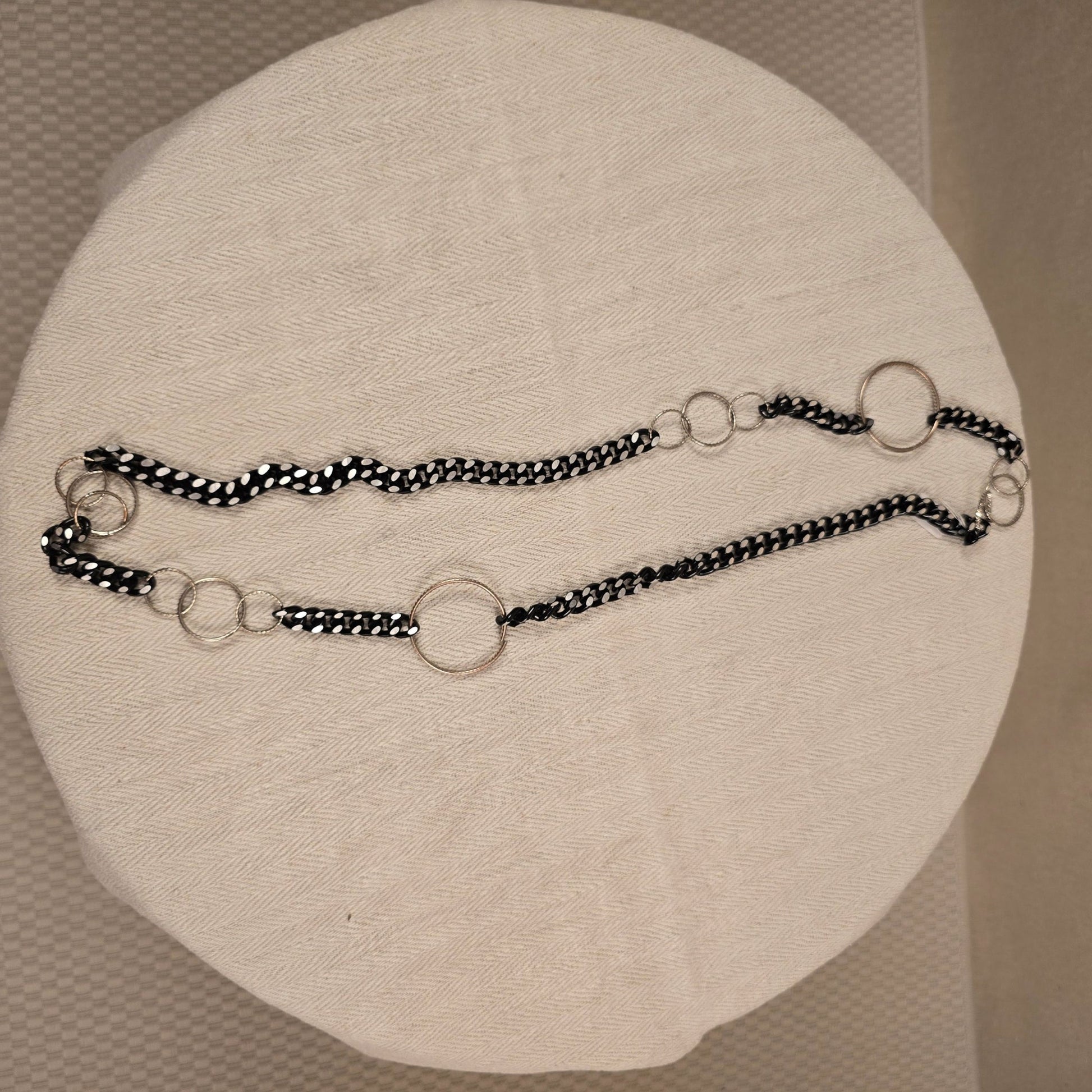 Halskette „Chain Reaction“ mit silberfarbenen Gliedern und schwarzem Stoffband mit weißen Punkten – auffälliger, flexibler Materialmix